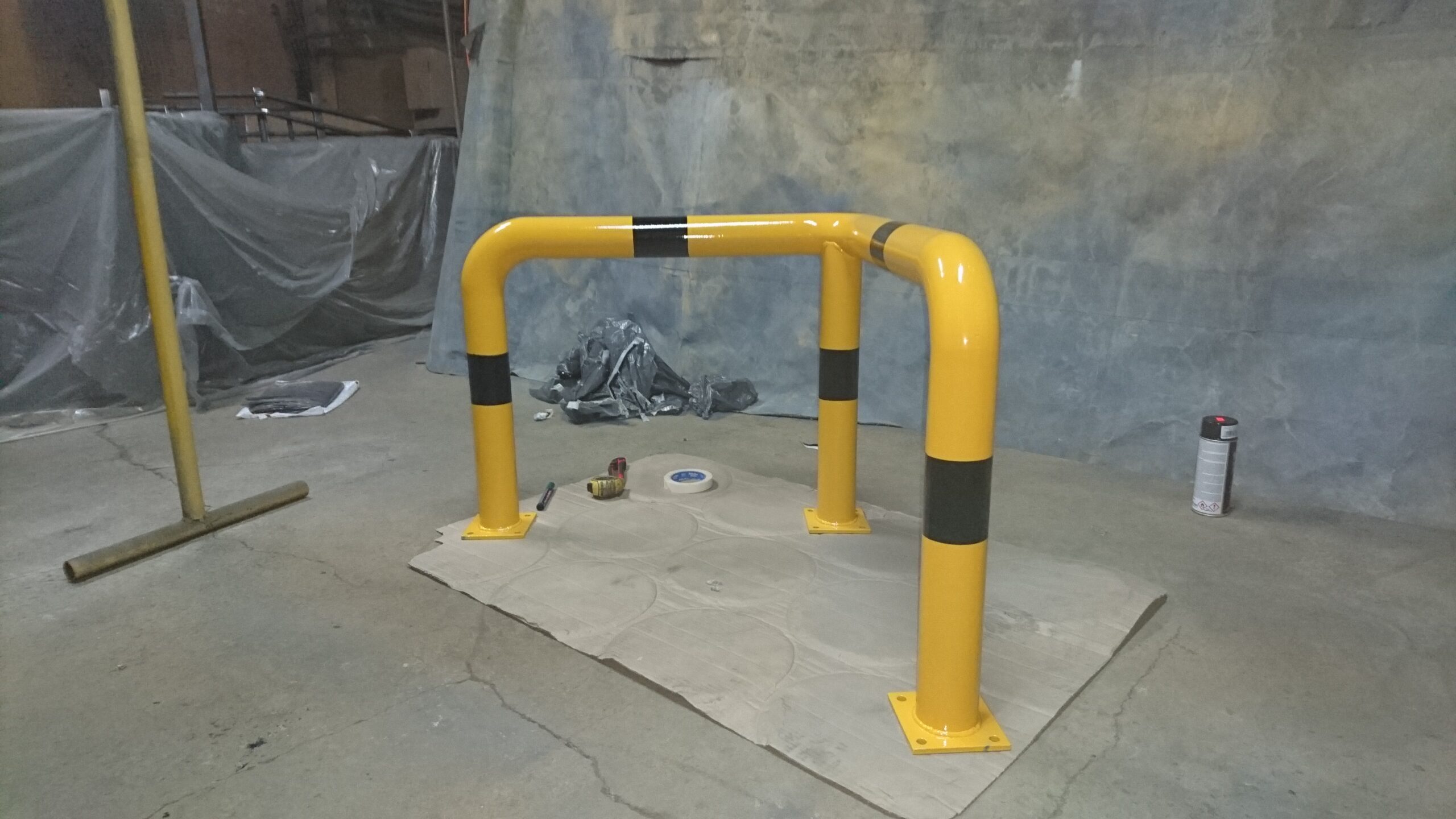 Bariera ochronna przemysłowa w kolorze żółto-czarnym zamontowana na posadzce hali