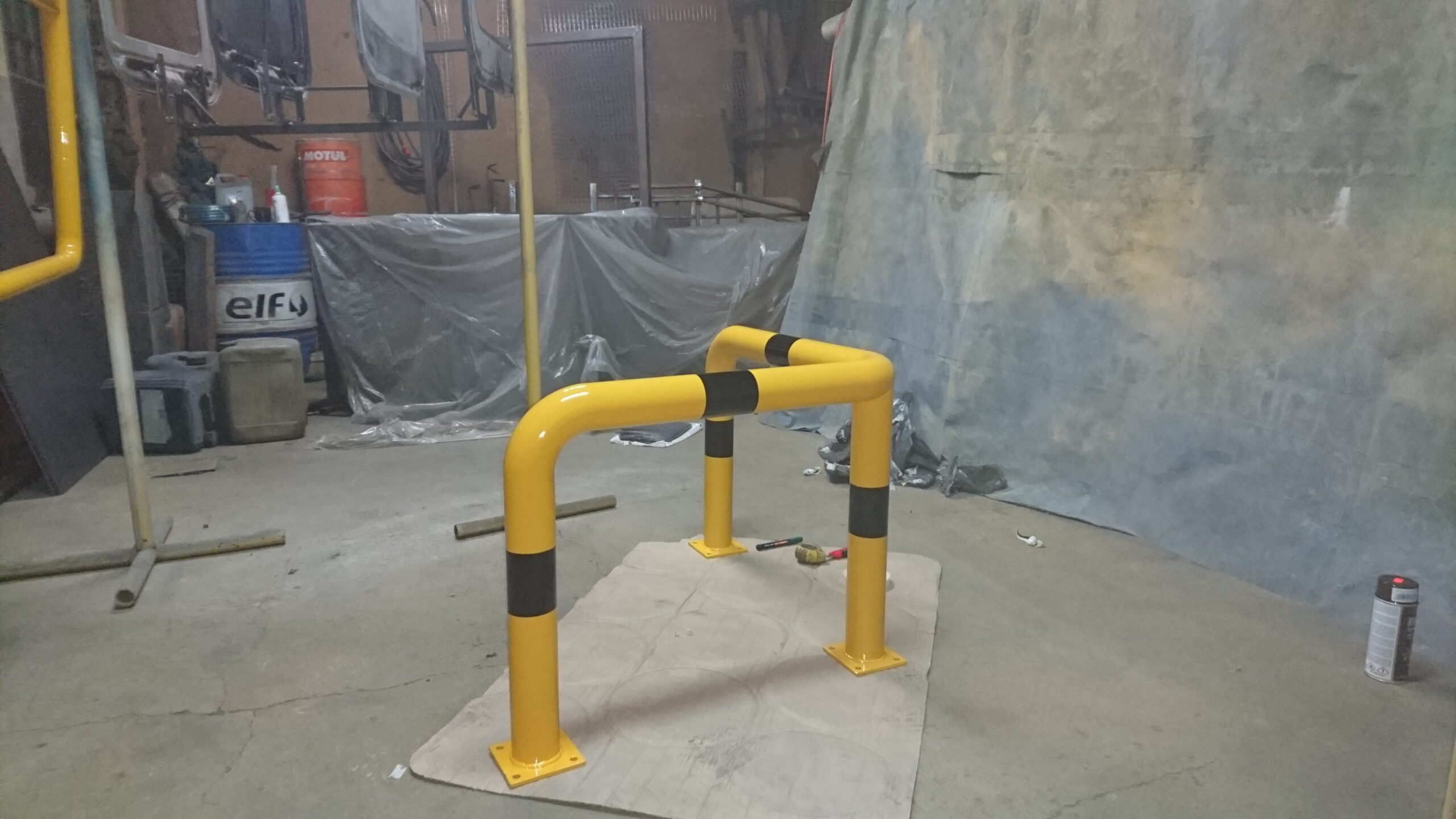 Bariera ochronna przemysłowa w kolorze żółto-czarnym zamontowana na posadzce hali