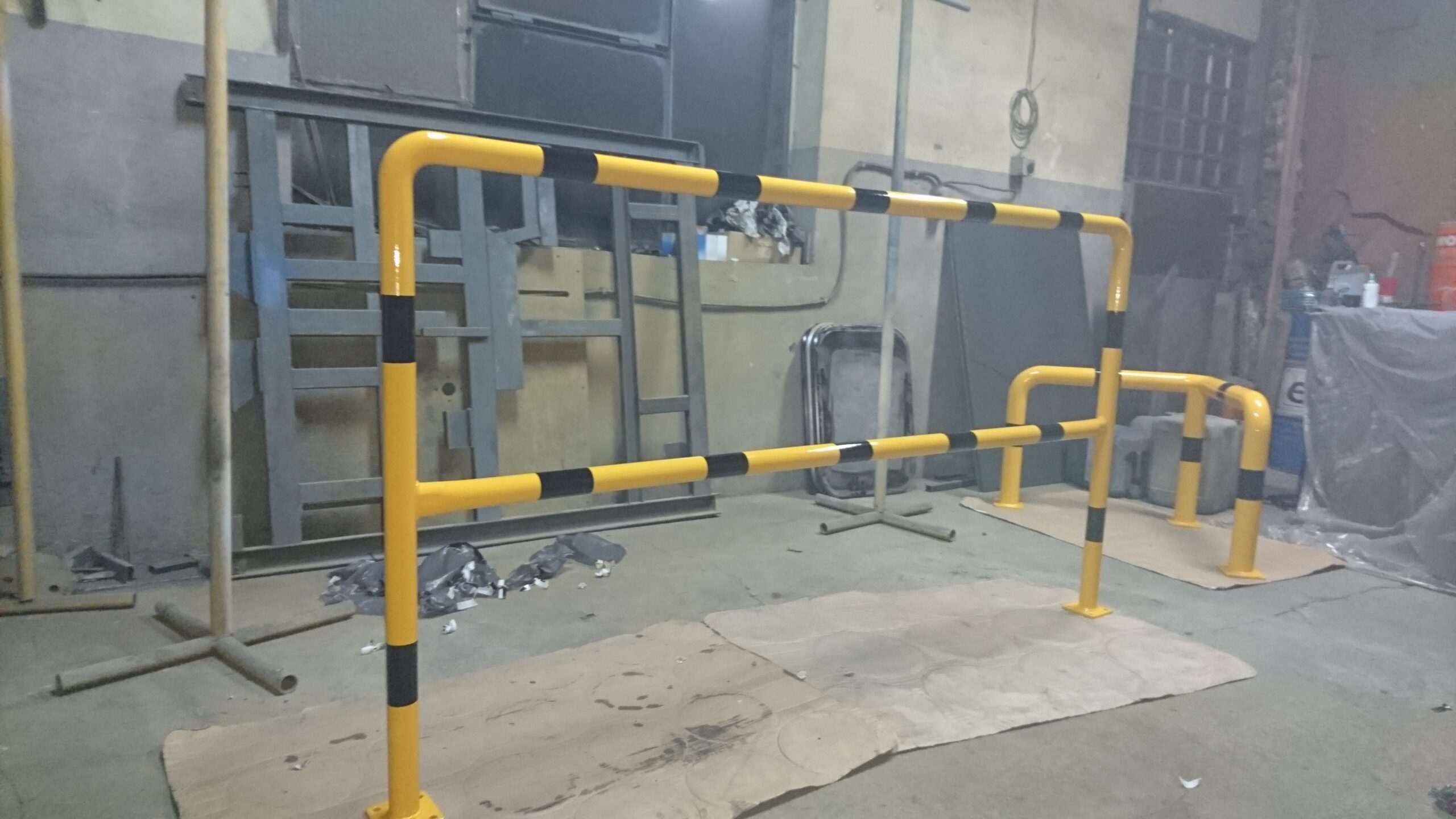 Bariera ochronna przemysłowa w kolorze żółto-czarnym zamontowana na posadzce hali