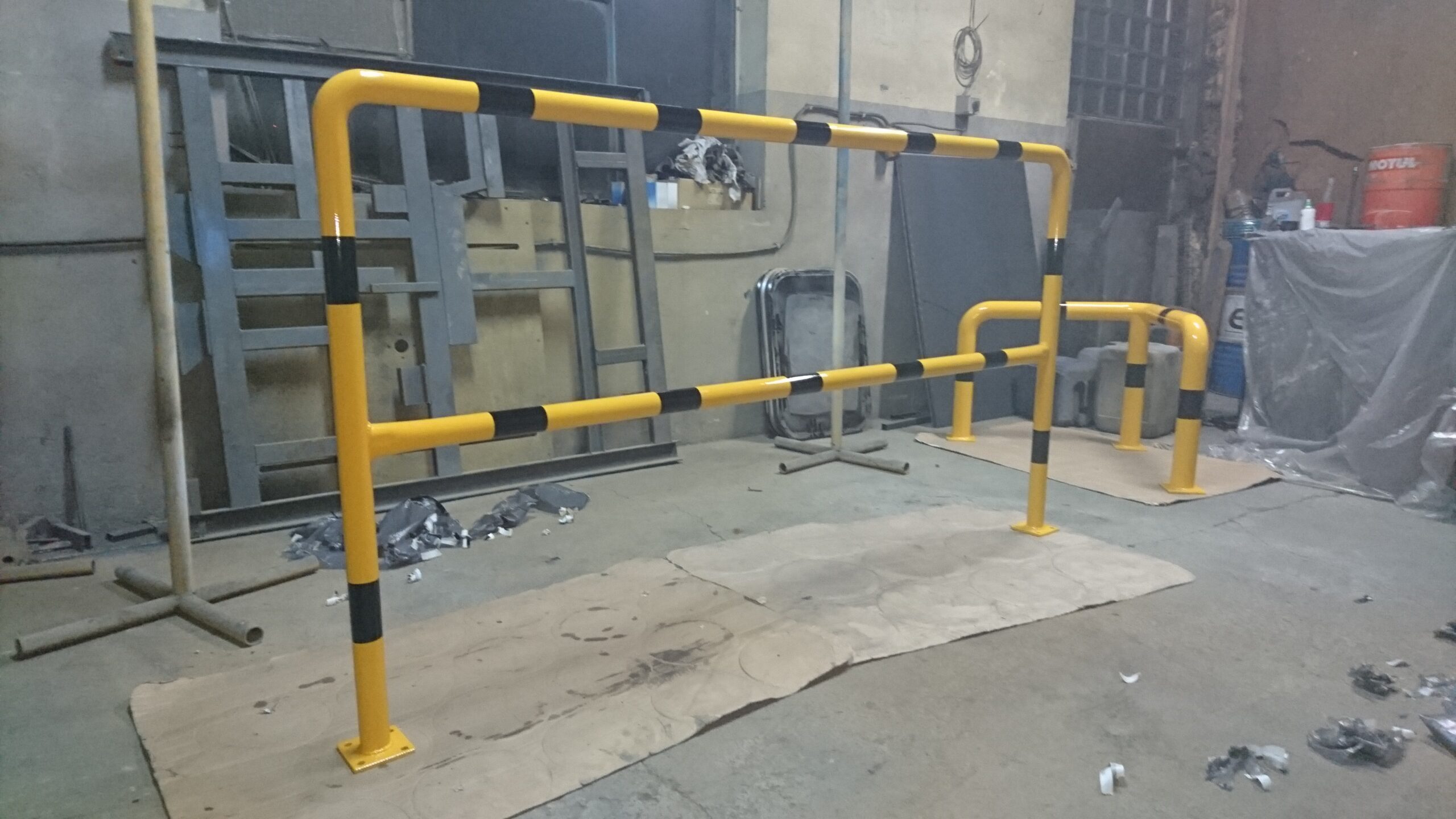 Bariera ochronna przemysłowa w kolorze żółto-czarnym zamontowana na posadzce hali