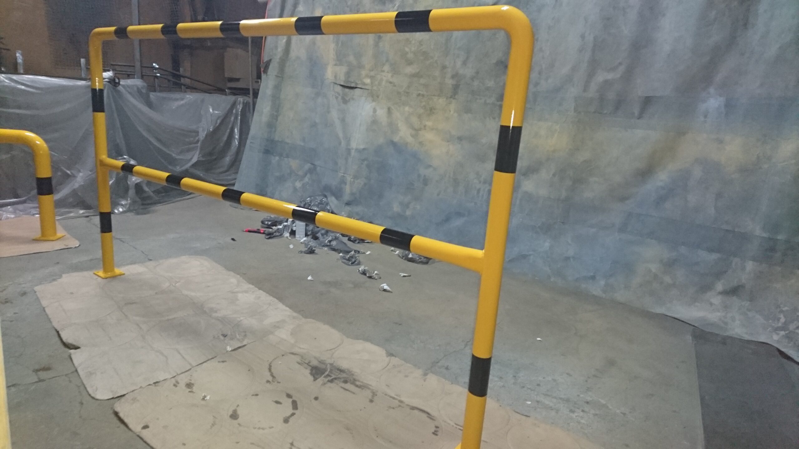 Bariera ochronna przemysłowa w kolorze żółto-czarnym zamontowana na posadzce hali