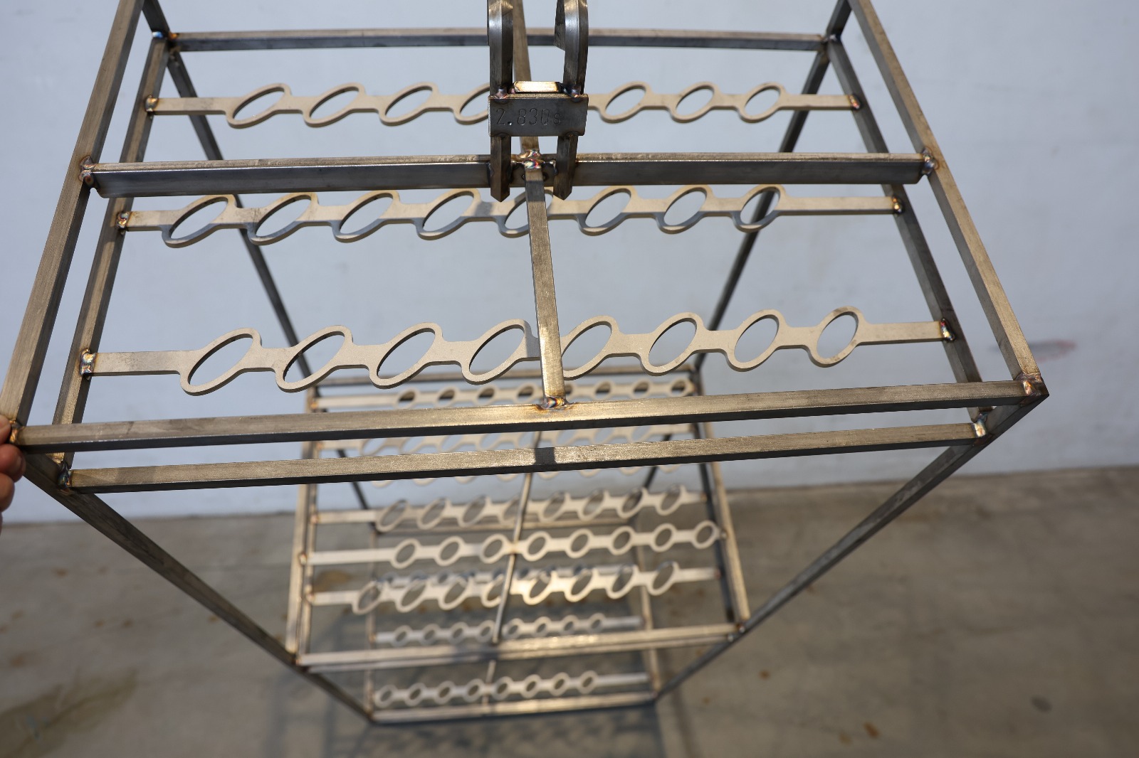 Metalowa zawieszka przemysłowa z rzędami haków, używana do zawieszania detali w procesach produkcyjnych lub obróbki powierzchniowej.