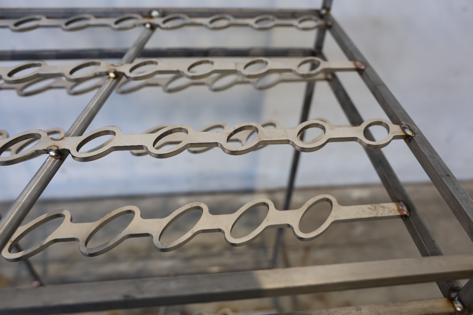 Metalowa zawieszka przemysłowa z rzędami haków, używana do zawieszania detali w procesach produkcyjnych lub obróbki powierzchniowej.