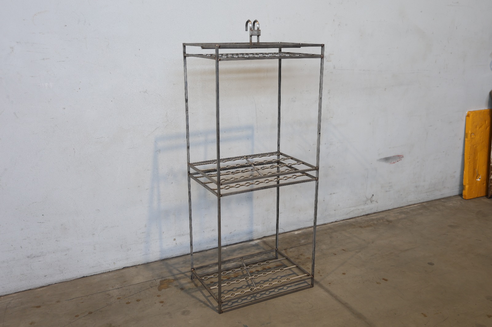 Metalowa zawieszka przemysłowa z rzędami haków, używana do zawieszania detali w procesach produkcyjnych lub obróbki powierzchniowej.